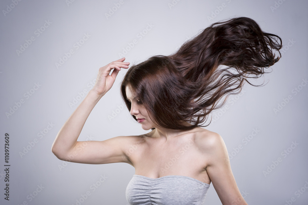 Naklejka premium Beautiful young woman with flowing hair in studio