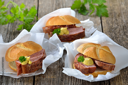 Street food bayerisch: Drei warme Leberkässemmeln mit Senf auf Wickelpapier mit Serviette - Bavarian street food: Three rolls with meat loaf and mustard on wrapping paper with white napkins photo