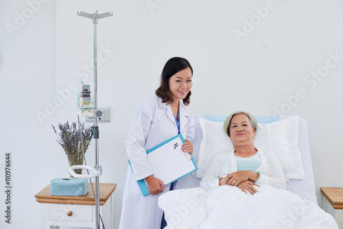 Portrait of nurse and senior female patient in bed