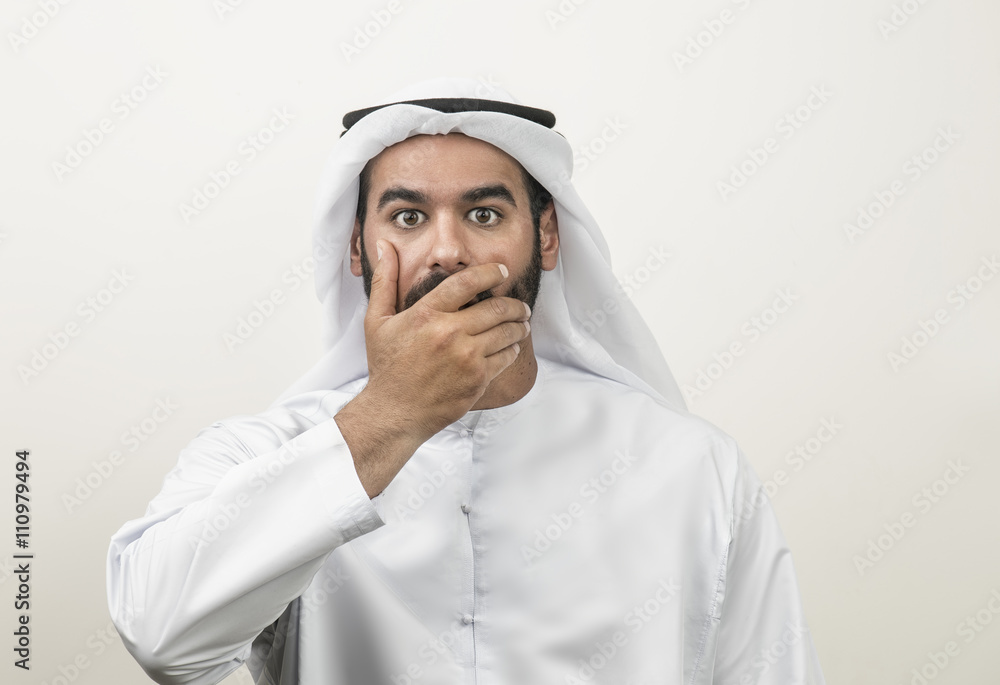 Portrait of a shocked Arabian man covering his mouth , Arabian g Portrait of a shocked Arabian man covering his mouth , Arabian g