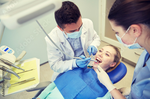 male dentist treating female patient teeth