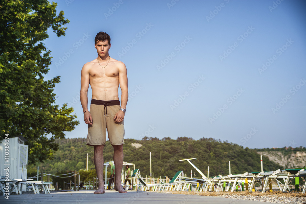 Young shirtless athletic man standing at the beach