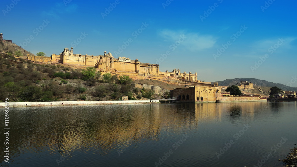 Ancient magnificent Amber fort towering on a rocky hill reflecte
