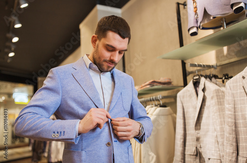 happy young man trying jacket on in clothing store