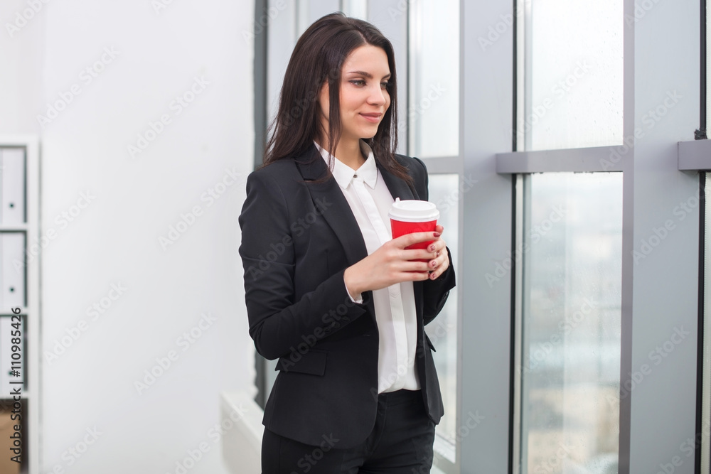 business woman standing at  window with cup