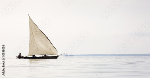 Traditional fisherman boat in Zanzibar on ocean with rainy cloud photo