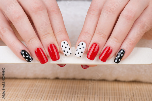 Manicure - Beauty treatment photo of nice manicured woman fingernails. Very nice feminine nail art with nice red, white and black nail polish.
