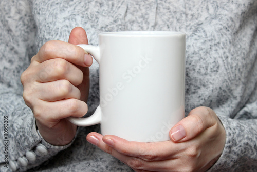Obraz na plátně Girl is holding white cup in hands. White mug in woman's hands.
