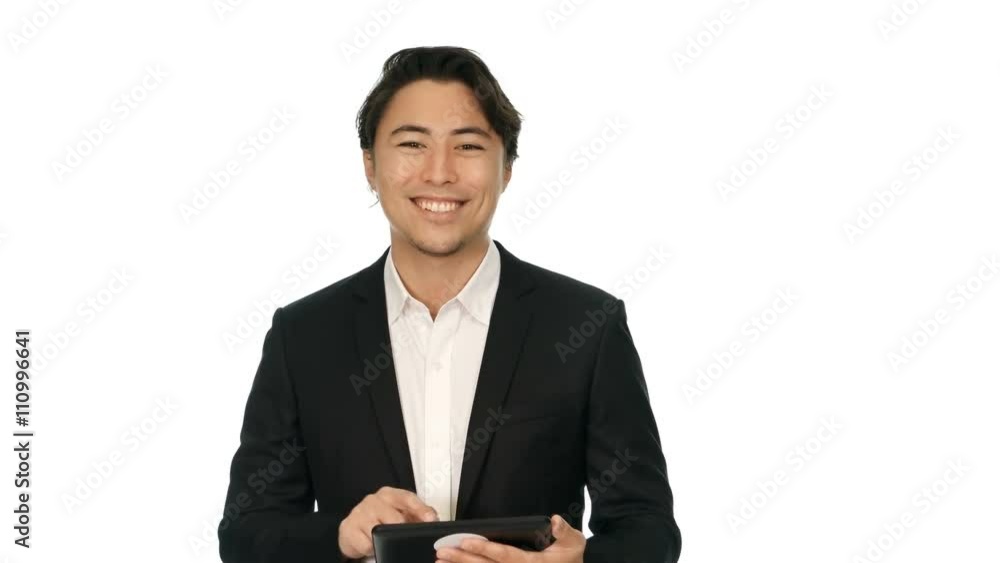 Handsome businessman in a black suit and white shirt, walking in front of a white background working on a digital tablet. Handsome businessman in a black suit and white shirt, walking in front of a white background working on a digital tablet.