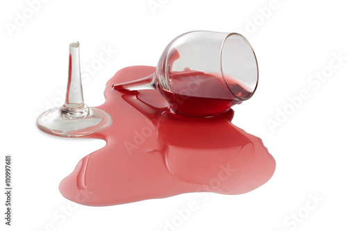 Broken glass and spilled red wine on white background