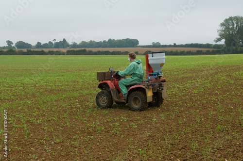 Young male farmer wearing protective mask spray crop in field photo