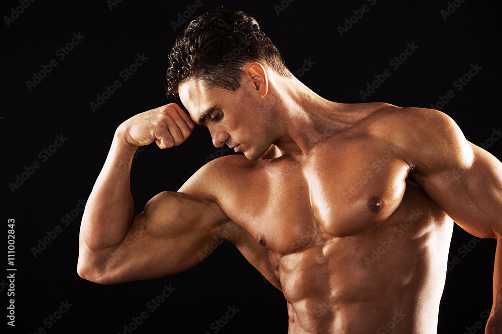 Strong Athletic Man showing muscular body on a black background.Muscular man on black background Strong Athletic Man showing muscular body on a black background.Muscular man on black background