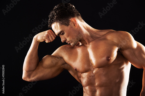Strong Athletic Man showing muscular body on a black background.Muscular man on black background