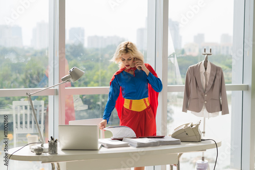 Schilderij op canvas Powerful superwoman talking on phone and working with documents  in office
