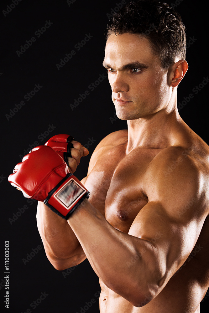 Strong Athletic Man showing muscular body on a black background.muscular man with boxing gloves on a black background.muscular man wearing gloves for mixed martial arts on a black background