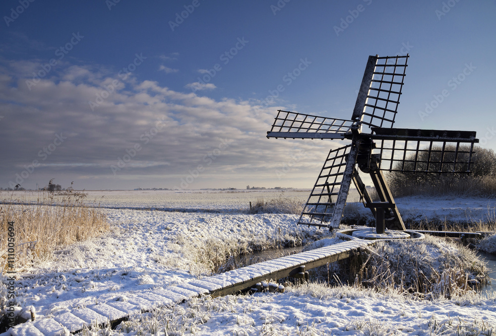 Tjasker mill de Zandpoel in a winter landscape near the Frisian village Wijckel
