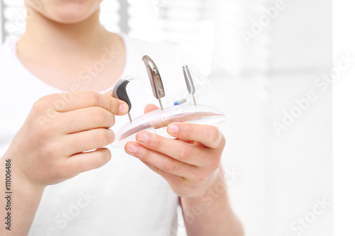 Aparaty słuchowe.Dziewczynka ogląda rodzaje aparatów słuchowych 