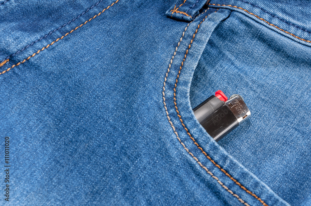 The pocket of jeans with lighter. Cloth background