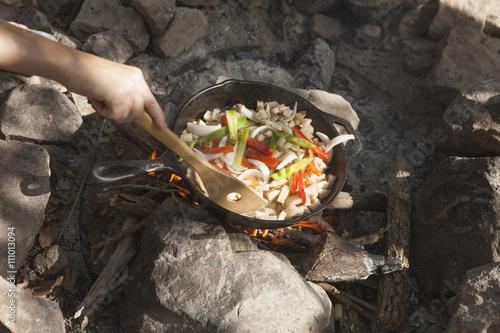 Hand of teenage boy cooking stir fry on campfire, Indiahoma, Oklahoma, USA photo