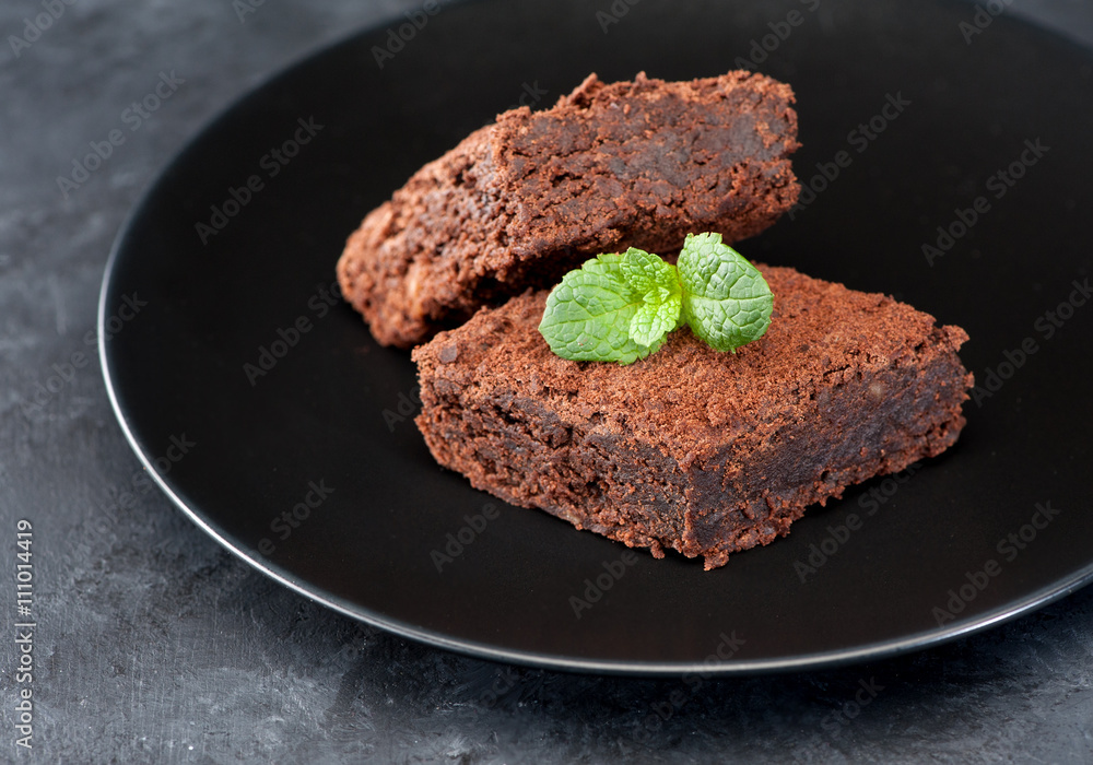 Chocolate brownie cake on a plate, black stone background Chocolate brownie cake on a plate, black stone background