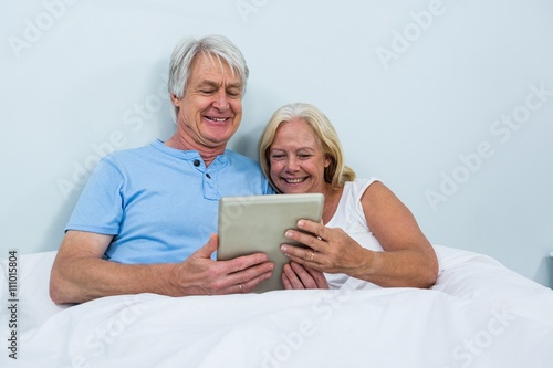 Senior couple using digital tablet while relaxing at home