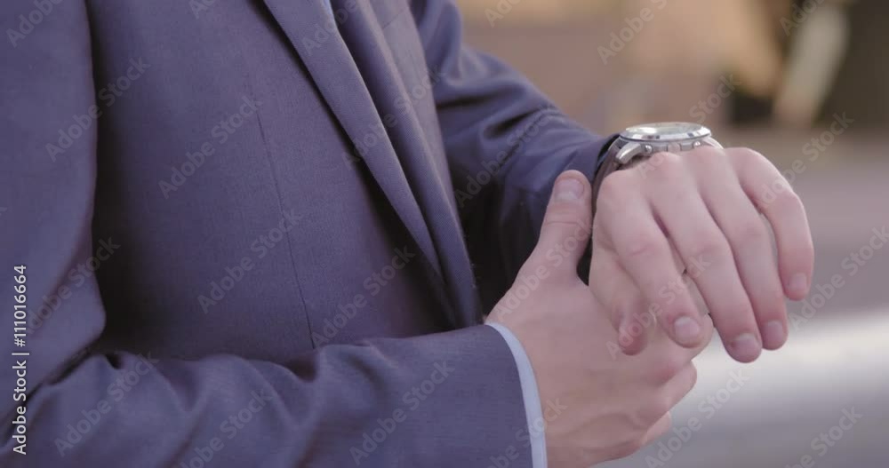 Detail of hands as young man in business suit checks time on his wrist watch on streets of Downtown Los Angeles. Slow motion recorded at 60fps. Detail of hands as young man in business suit checks time on his wrist watch on streets of Downtown Los Angeles. Slow motion recorded at 60fps.