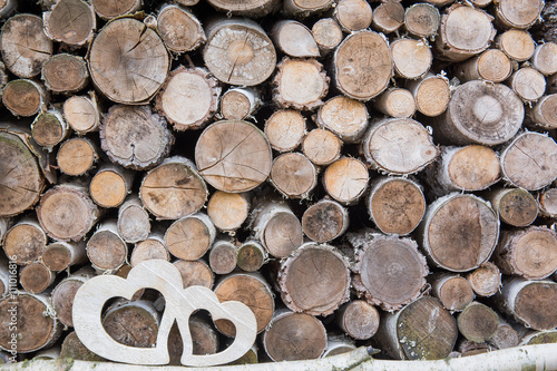Two wooden hearts on background of firewood 