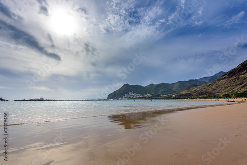Beach Las Teresitas with water and waves on yellow sand on coast or shore of Atlantic ocean on Tenerife Canary island