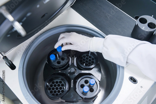 Cancer research laboratory, hand of scientist placing cells into centrifuge