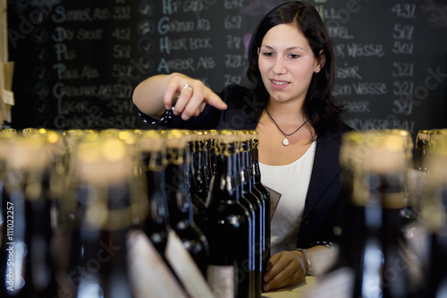 Woman counting bottles of wine in shop