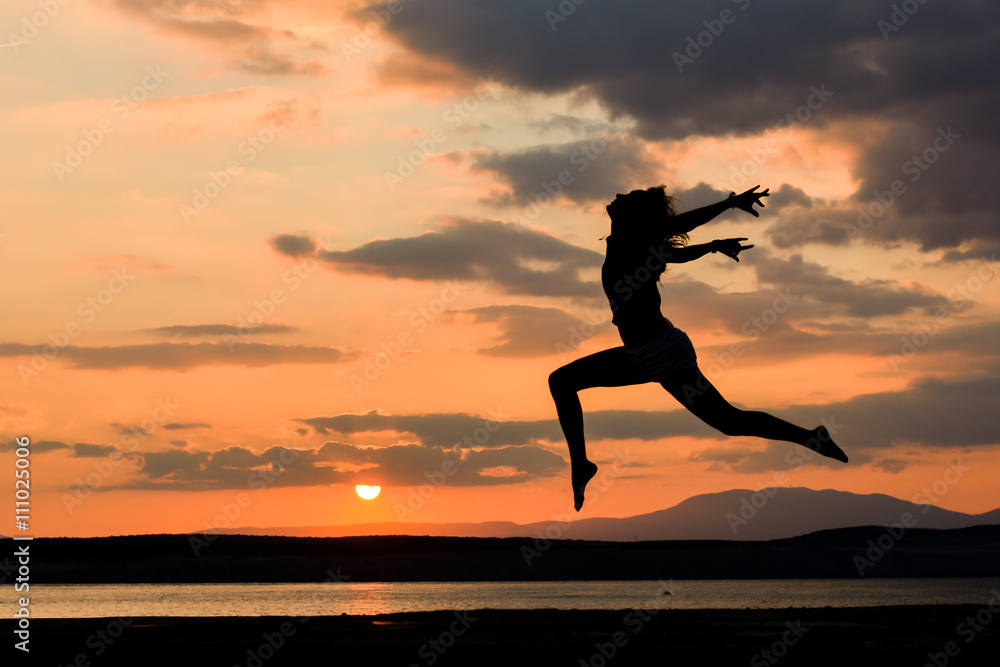 Girl jumping at sunset near the sea water