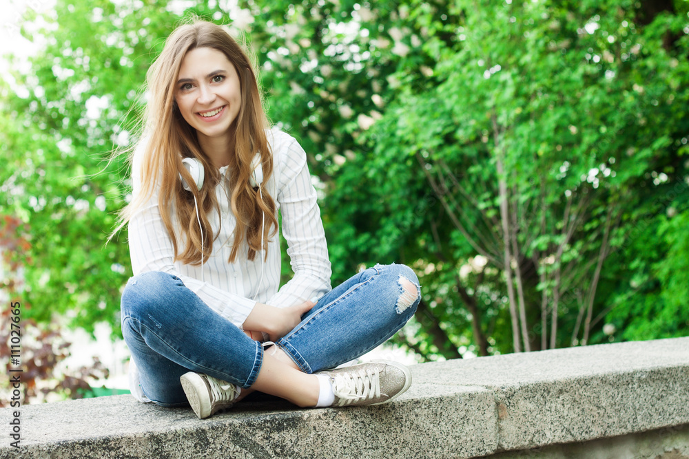 Obraz premium beautiful girl sitting outdoors in park and smiling