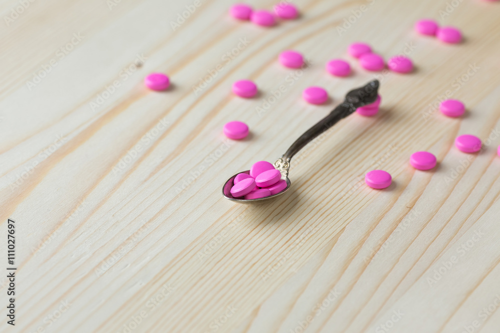 Pharmacy background. Full spoon of pills on a wooden table. Medicine. Natural background. Capsule on a spoon. Close up 