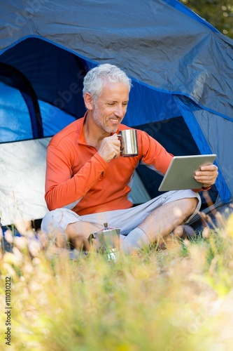 Mature man smiling and holding mug and laptop