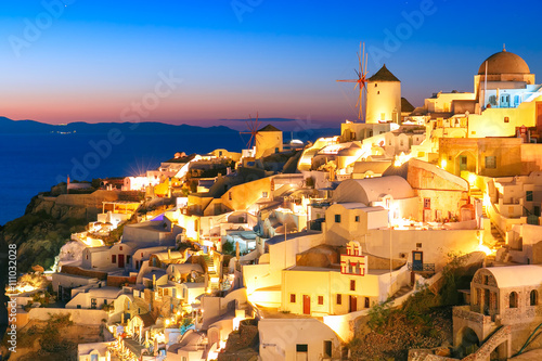 Windmills in Oia on the island Santorini, white houses and church during twilight blue hour, Greece