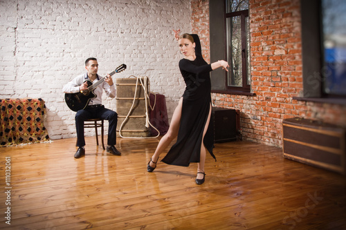 Young woman dancing flamenco and a man playing the guitar