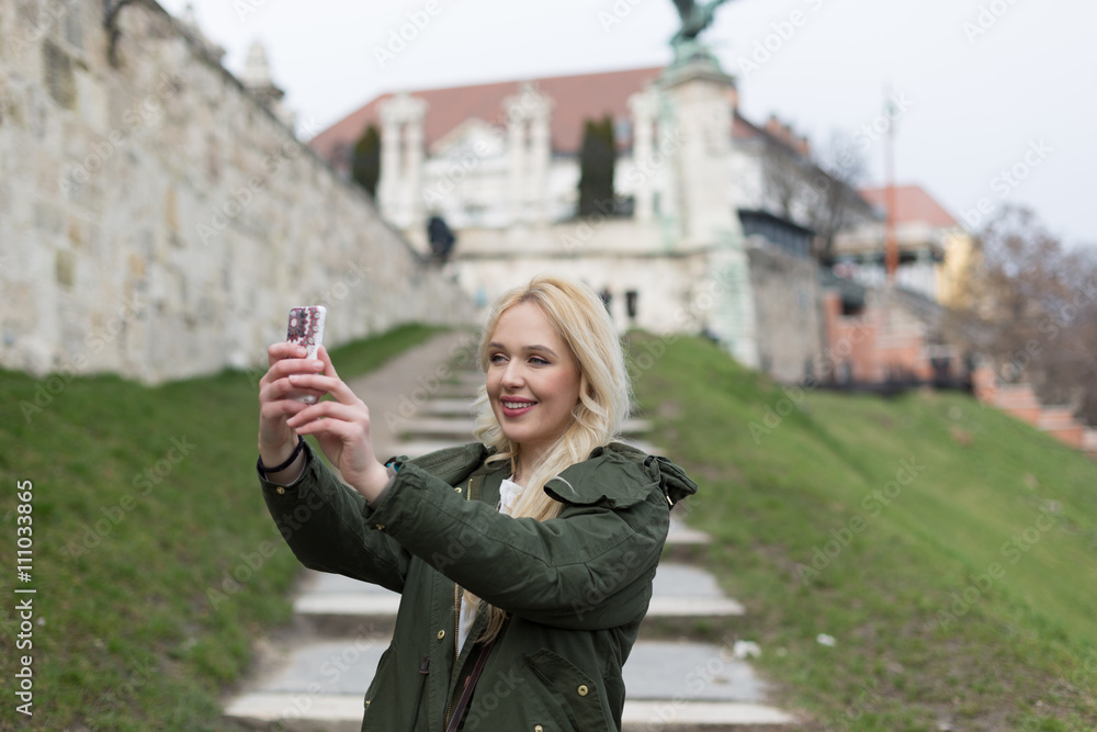 Fototapeta premium Beautiful young blonde tourist woman taking photographs.