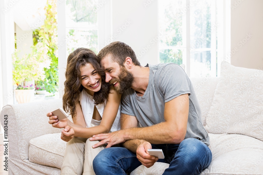 Smiling young couple looking at mobile phone