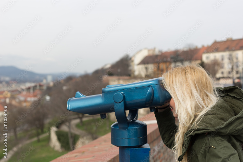Woman seeing the city over a river through binocular.