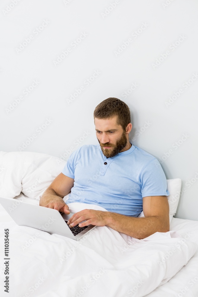 Man using laptop on bed Man using laptop on bed