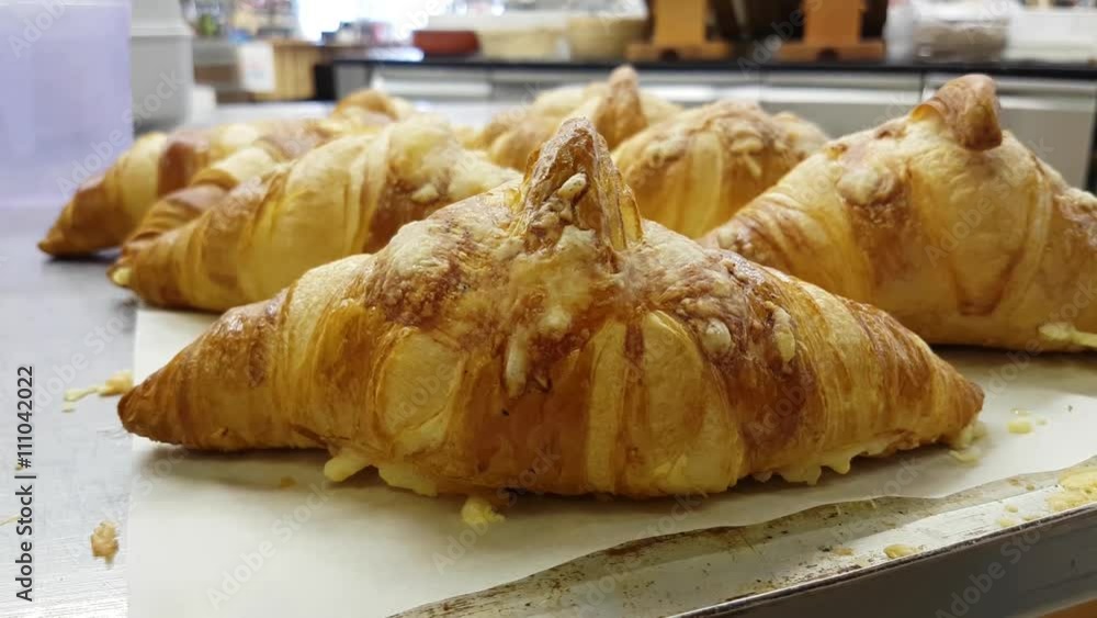 Lots of cheese topped croissants, at a bakery table Lots of cheese topped croissants, at a bakery table