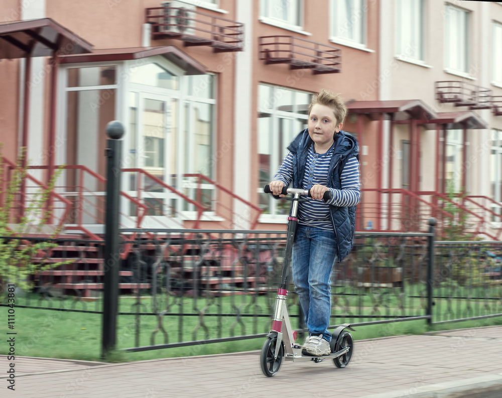 Obraz premium boy on scooter moving along the street