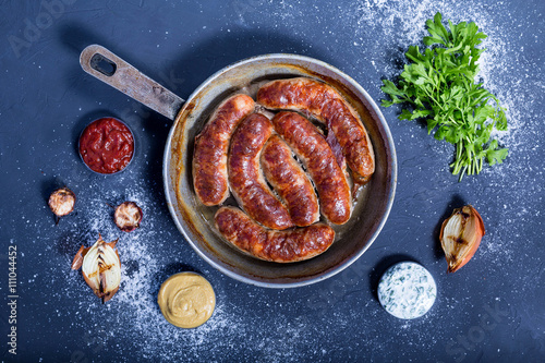 Country style oven-baked sausages in a frying pan, sauce