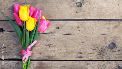Fototapeta Naklejka Na Ścianę i Meble -  Bunch of bright yellow and pink spring tulips on vintage wooden