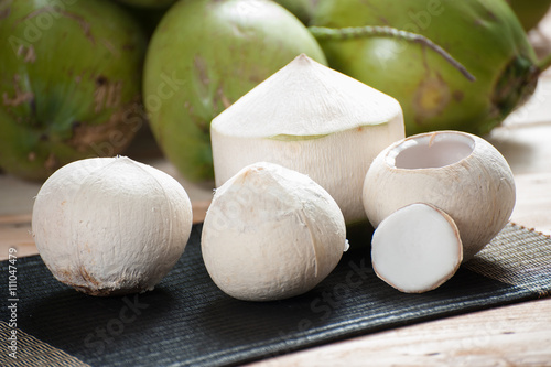 peeling coconut on mat with green coconut background