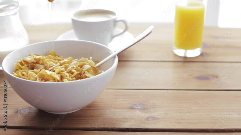 honey pouring to corn flakes on wooden table honey pouring to corn flakes on wooden table
