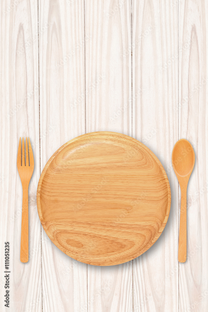 Empty wood plate with spoon fork on white table Empty wood plate with spoon fork on white table