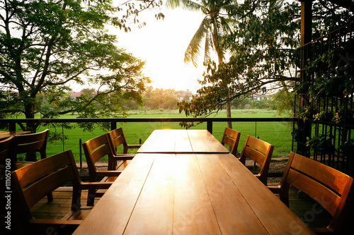 long wooden table. with six wooden chairs ,metal fence.and Rice