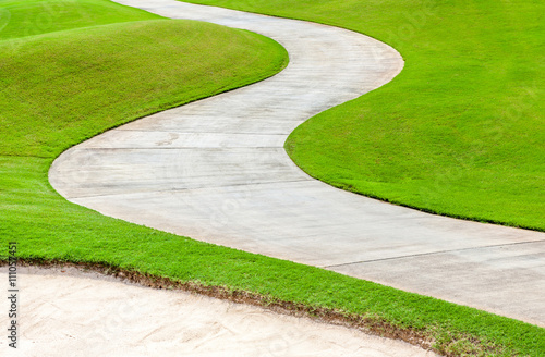 Path curving through green grass in golf course.