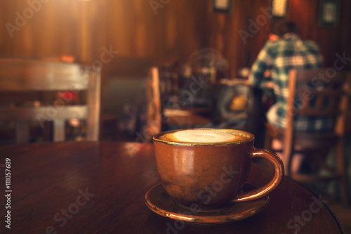 Cup of coffee on table in cafe with people vintage instagram effect - shallow depth of field